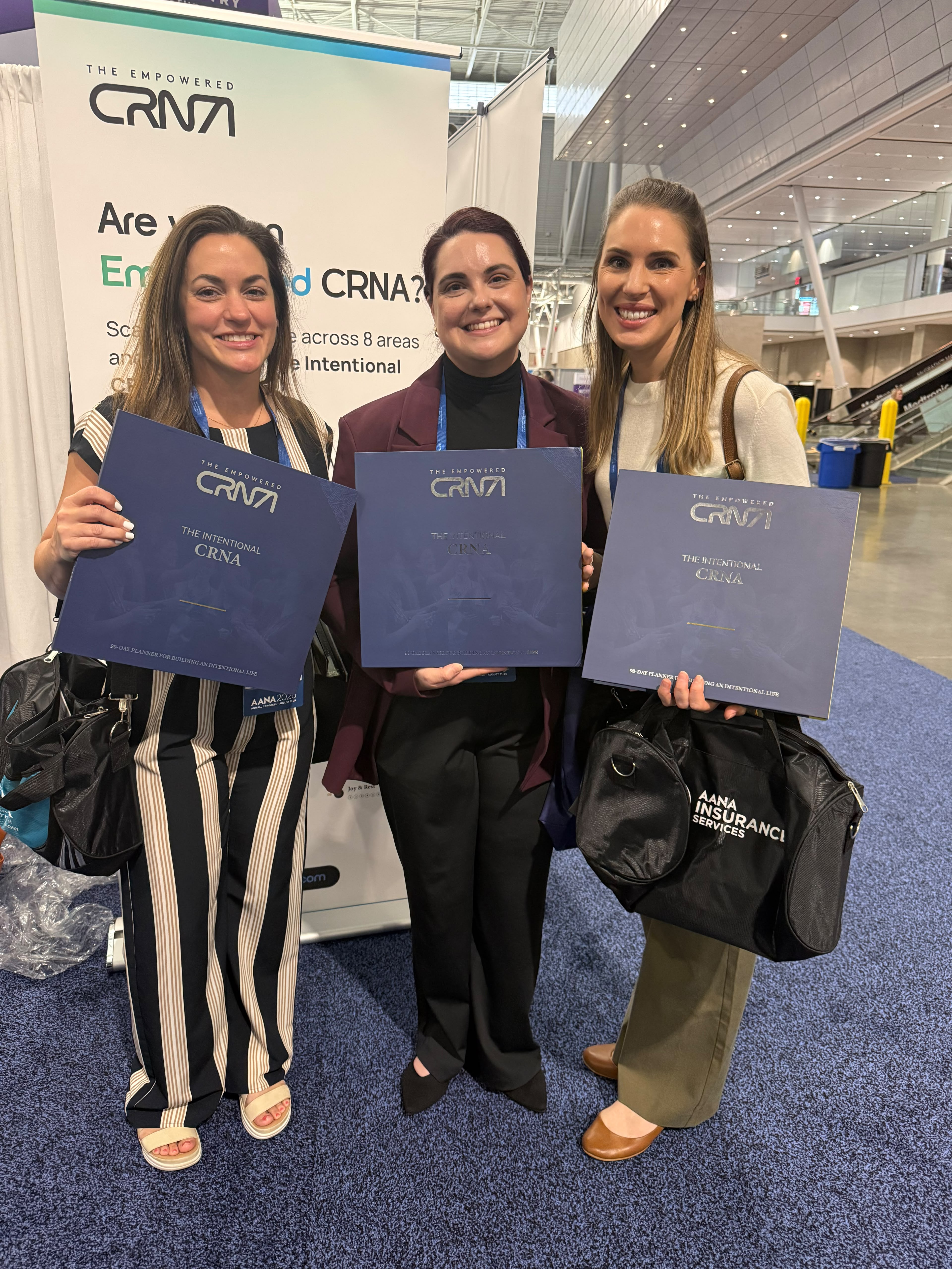 Three CRNAs holding The Intentional CRNA journals at AANA 2026