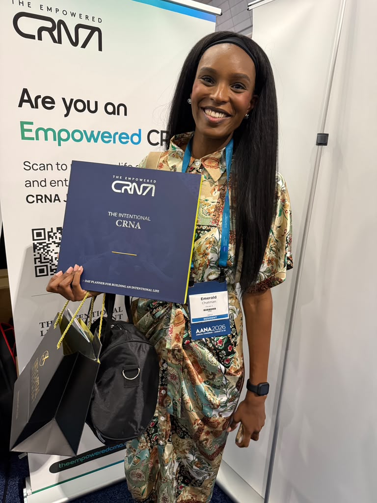 A CRNA smiling and holding a copy of The Intentional CRNA at the Empowered CRNA booth at AANA 2026